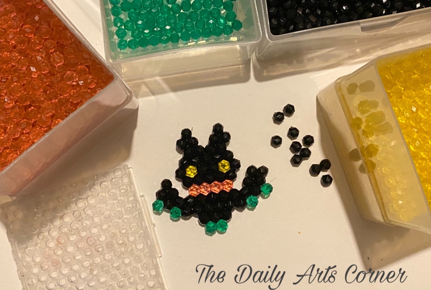 Aquabead bat banner picture of the Aquabeads and tools as well as materials needed around it.
